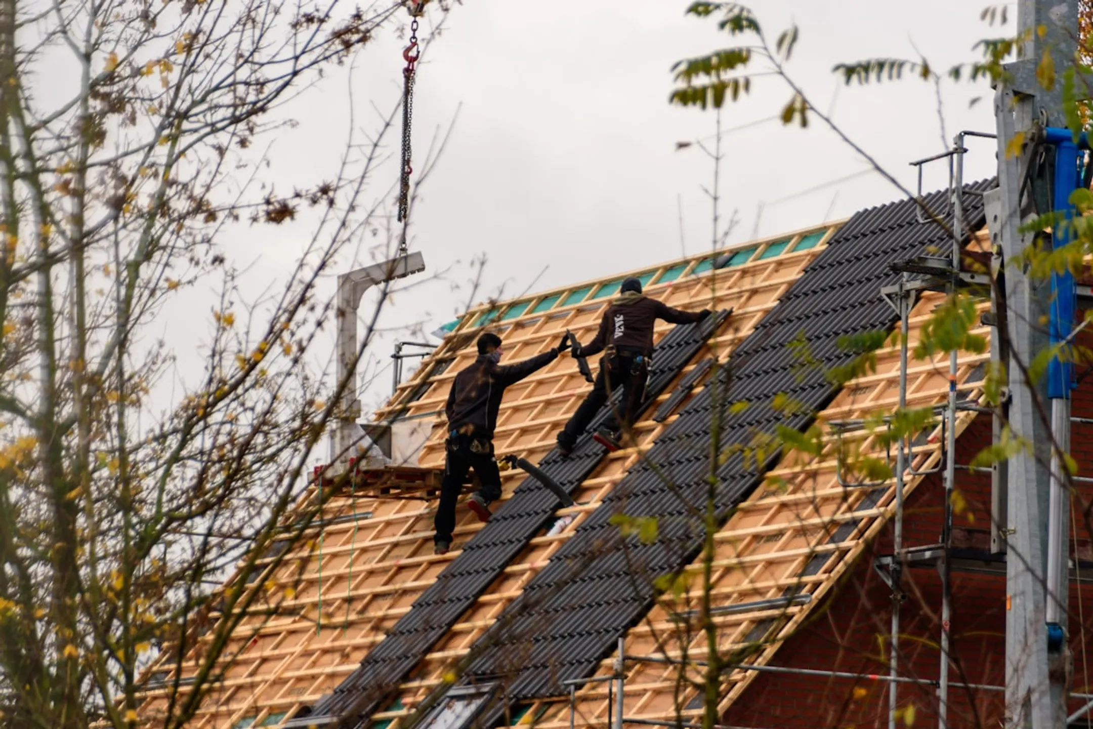 Construction workers installing new roof on residential home